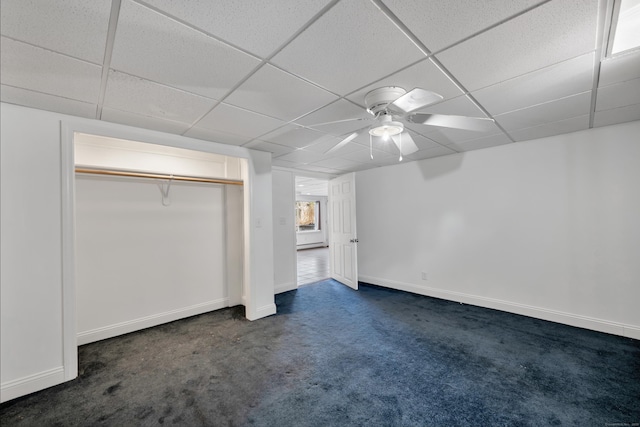 unfurnished bedroom with ceiling fan, baseboards, a closet, a paneled ceiling, and dark colored carpet