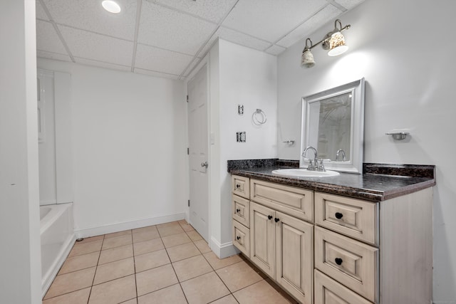 full bathroom featuring a tub, baseboards, tile patterned floors, vanity, and a paneled ceiling