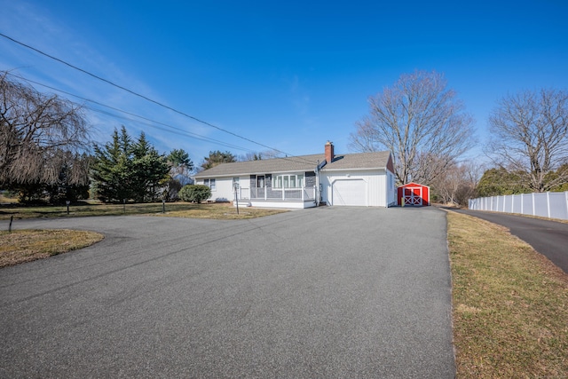 view of front of property featuring a chimney, driveway, an attached garage, and fence