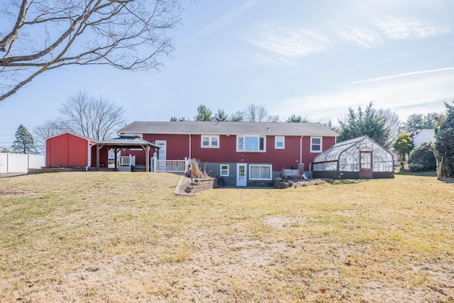 rear view of property with an outbuilding, a lawn, fence, a gazebo, and a greenhouse