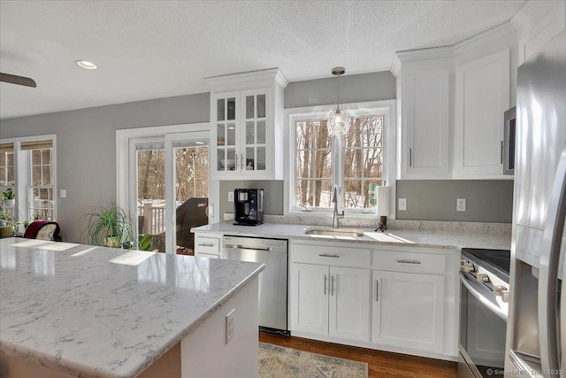 kitchen with a healthy amount of sunlight, white cabinetry, stainless steel appliances, and a sink