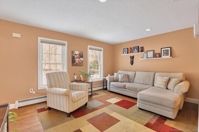 living area featuring a textured ceiling, baseboard heating, and wood finished floors