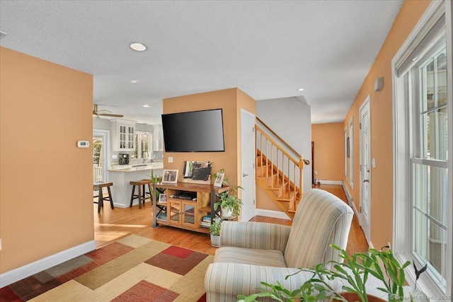 interior space featuring baseboards, wood finished floors, stairs, a textured ceiling, and recessed lighting