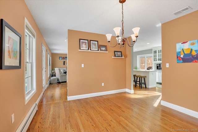 unfurnished dining area featuring a baseboard heating unit, visible vents, baseboards, light wood finished floors, and an inviting chandelier