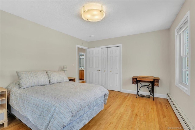 bedroom featuring light wood-style floors, a baseboard radiator, baseboards, and a closet