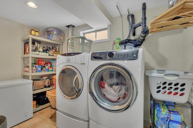 clothes washing area featuring laundry area, washing machine and clothes dryer, and light tile patterned floors