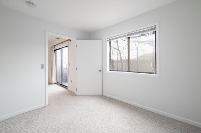 unfurnished room with light carpet and baseboards