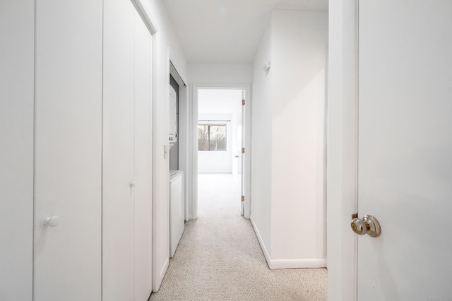 corridor featuring light carpet, washer / clothes dryer, and baseboards