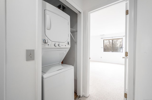 clothes washing area with carpet floors, stacked washing maching and dryer, and laundry area