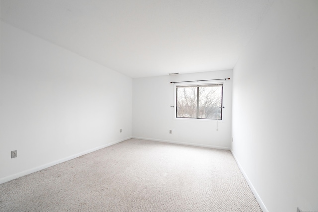 unfurnished room featuring light carpet and baseboards