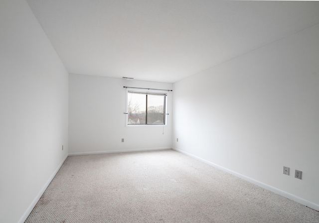 unfurnished room featuring light carpet and baseboards