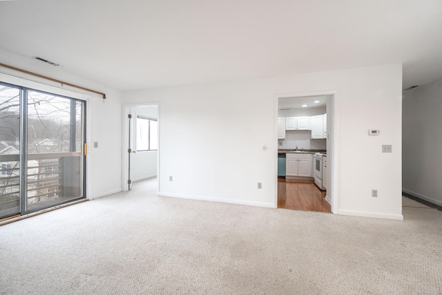 unfurnished living room featuring light carpet and baseboards