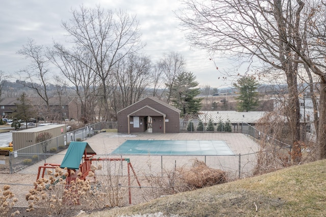 community pool with a playground, a patio, an exterior structure, fence, and an outdoor structure