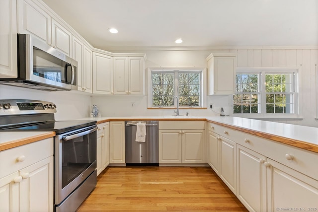 kitchen featuring light countertops, recessed lighting, light wood-style floors, stainless steel appliances, and a sink