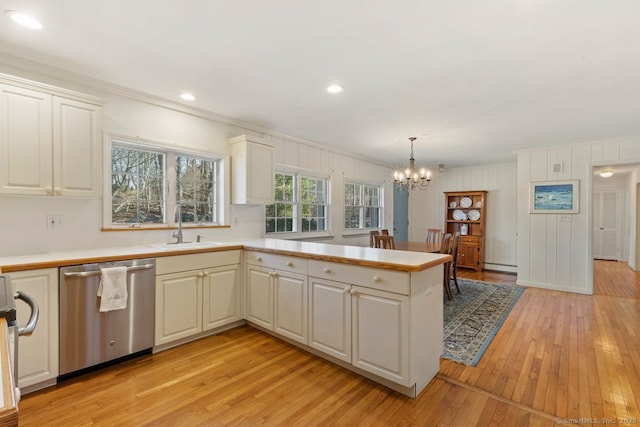 kitchen featuring a baseboard radiator, a peninsula, a sink, light countertops, and stainless steel dishwasher