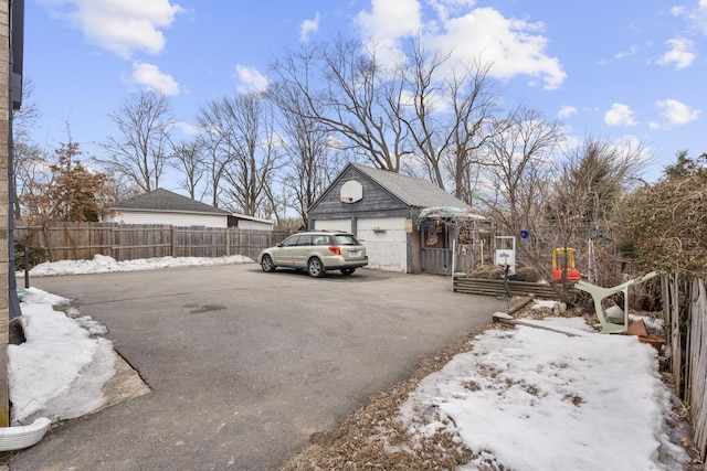 yard layered in snow with a garage, fence, and an outdoor structure