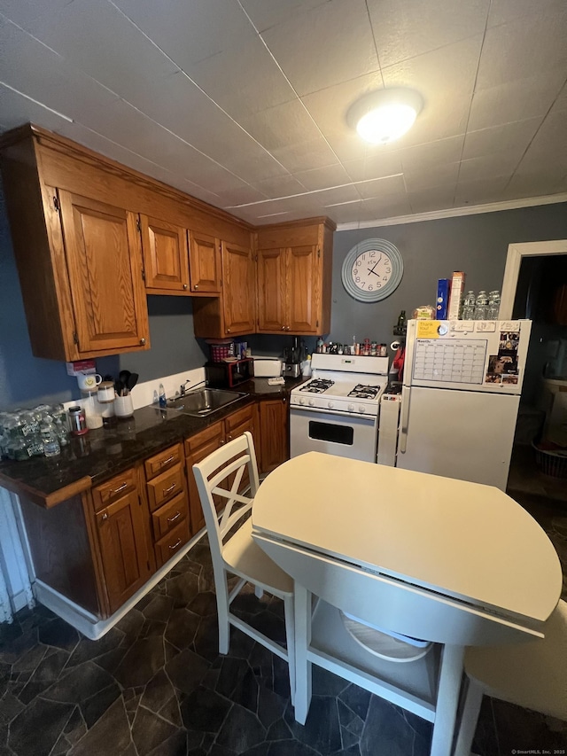 kitchen featuring dark countertops, white appliances, brown cabinets, and a sink