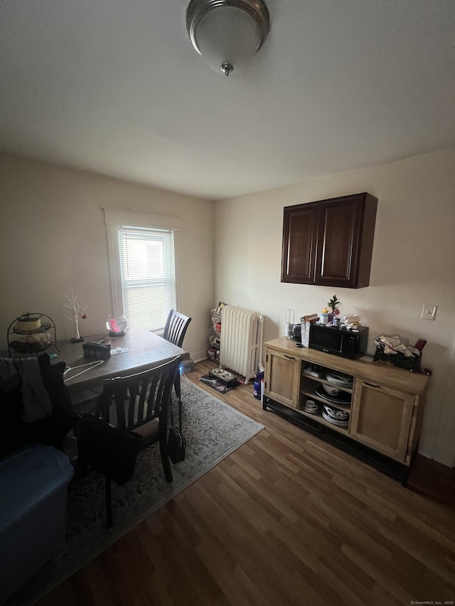 dining area with dark wood finished floors and radiator