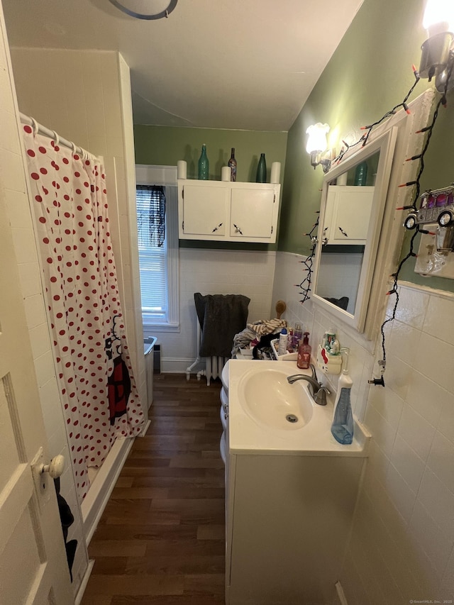 bathroom with a stall shower, tile walls, vanity, and wood finished floors