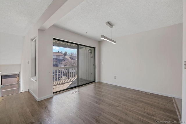 interior space with visible vents, a textured ceiling, baseboards, and wood finished floors