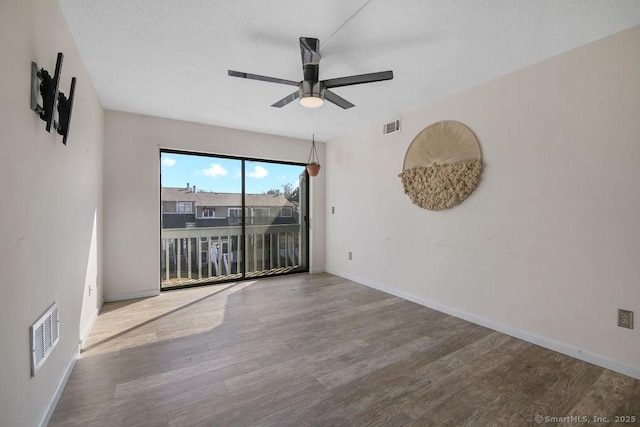 spare room with a textured ceiling, visible vents, and wood finished floors