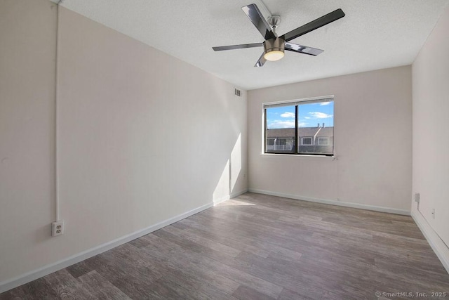 spare room featuring ceiling fan, a textured ceiling, wood finished floors, visible vents, and baseboards