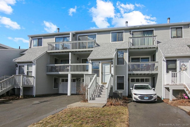 exterior space with driveway, an attached garage, and central AC