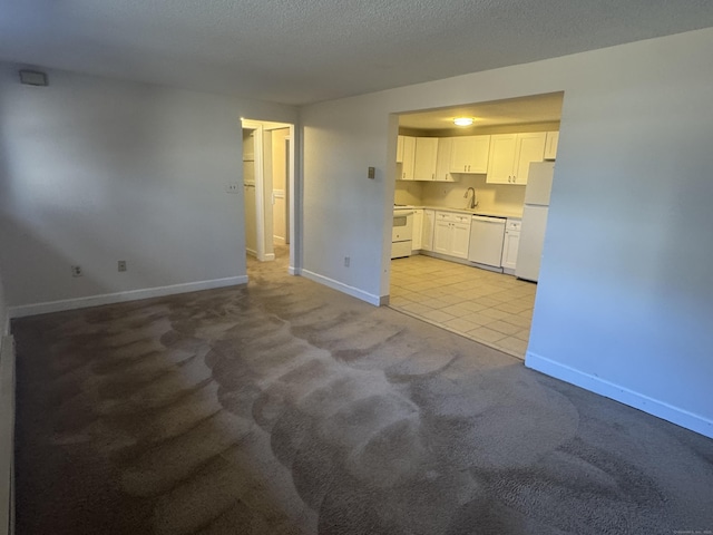 unfurnished living room featuring a textured ceiling, light tile patterned flooring, light colored carpet, a sink, and baseboards