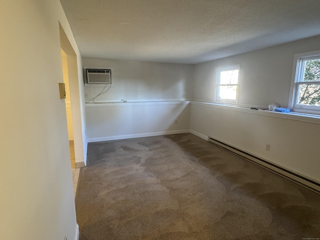 carpeted empty room with baseboards, a wall unit AC, a textured ceiling, and baseboard heating