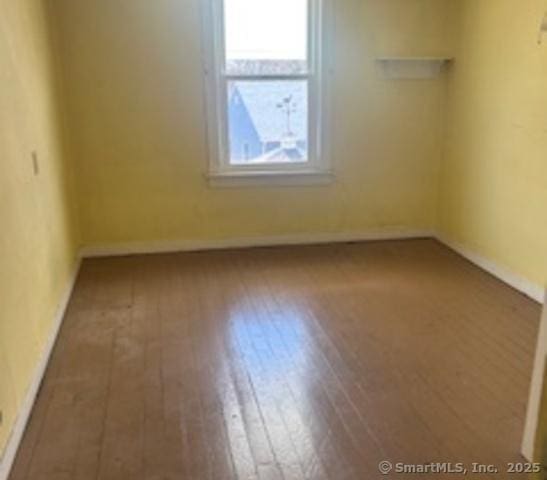 empty room featuring wood finished floors and baseboards