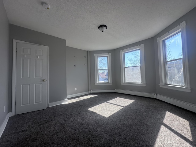 unfurnished room featuring baseboards, dark colored carpet, and a textured ceiling