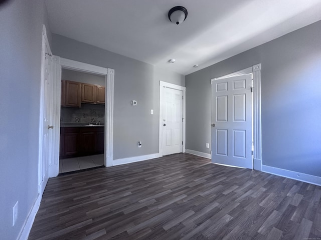 unfurnished bedroom with baseboards, dark wood-type flooring, and ensuite bathroom