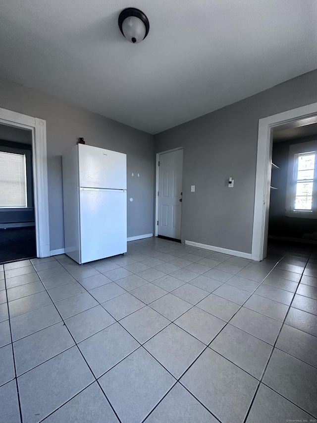 spare room featuring light tile patterned flooring and baseboards