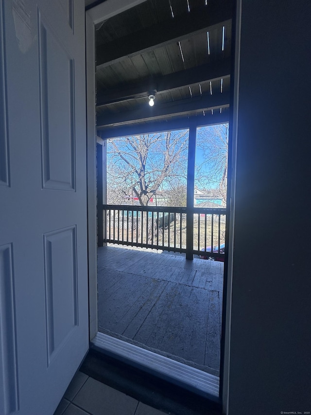 doorway to outside with dark tile patterned flooring, beamed ceiling, wood ceiling, and a healthy amount of sunlight