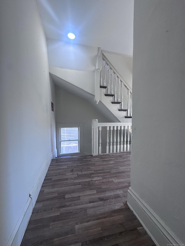 stairway with lofted ceiling, wood finished floors, and baseboards