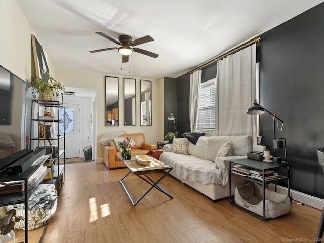 living area with wood finished floors, a ceiling fan, and baseboards