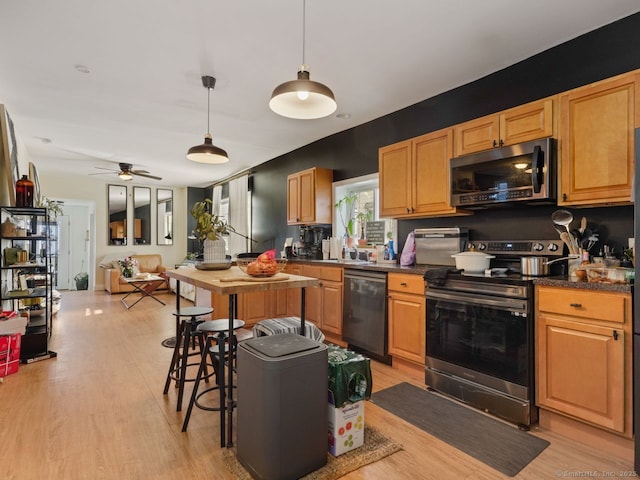 kitchen featuring stainless steel appliances, dark countertops, and light wood-style flooring