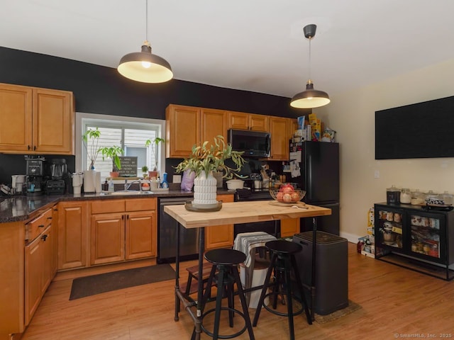 kitchen featuring light wood-type flooring, dishwashing machine, a sink, and freestanding refrigerator