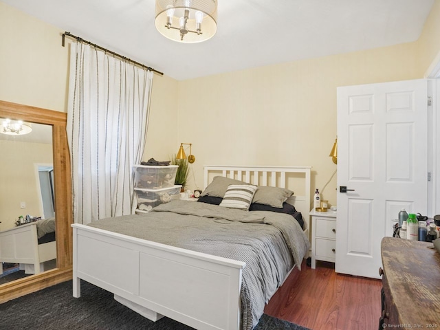 bedroom with dark wood-style floors and a notable chandelier