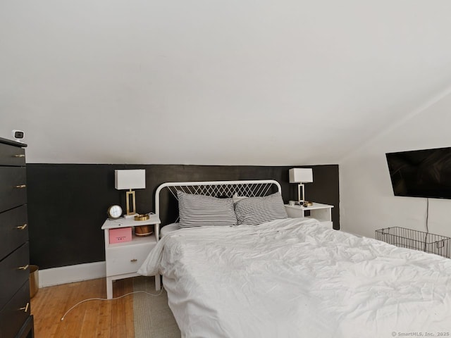 bedroom featuring baseboards, vaulted ceiling, and wood finished floors