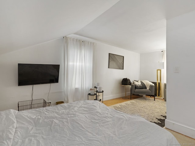 bedroom featuring lofted ceiling, baseboards, and wood finished floors