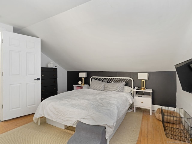 bedroom featuring light wood-type flooring and vaulted ceiling