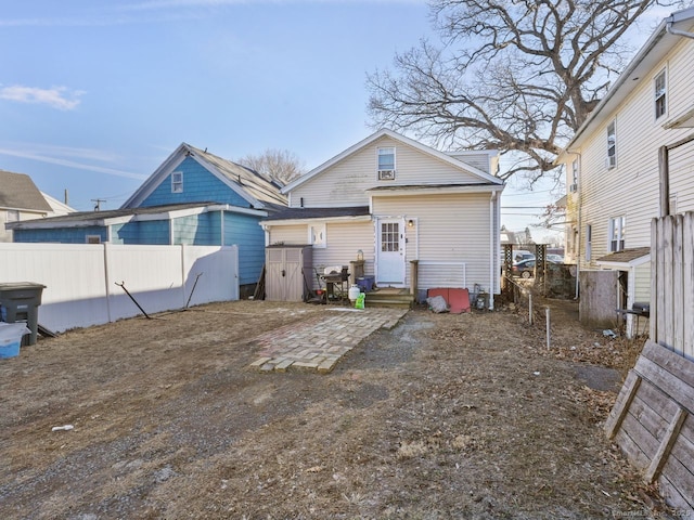 rear view of house featuring entry steps and fence