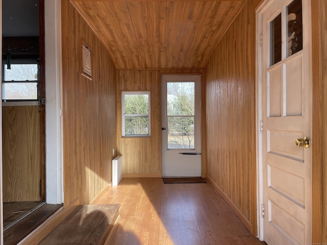 doorway to outside with baseboards, wood finished floors, wooden walls, and wooden ceiling