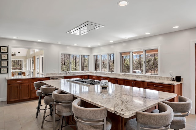 kitchen featuring recessed lighting, light stone countertops, a breakfast bar, and stainless steel gas cooktop