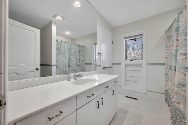 bathroom with a wainscoted wall, a shower with curtain, tile walls, tile patterned flooring, and vanity