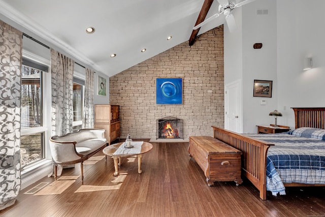 bedroom featuring wood finished floors, visible vents, high vaulted ceiling, beam ceiling, and a fireplace