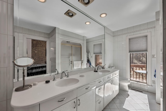 bathroom with tile walls, toilet, tile patterned floors, and a sink