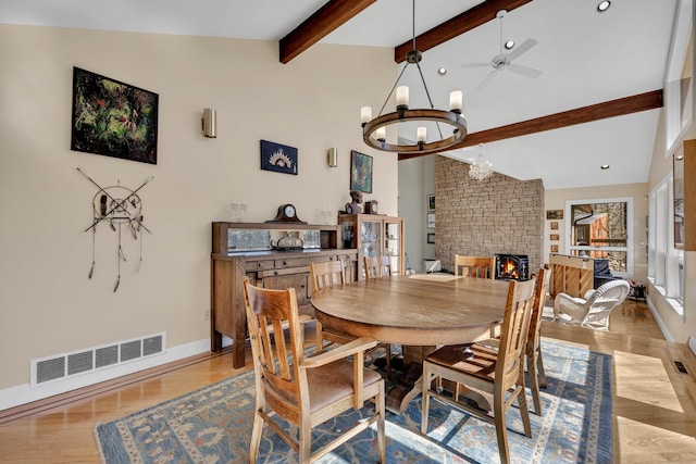 dining area with wood finished floors, visible vents, baseboards, a fireplace, and beamed ceiling