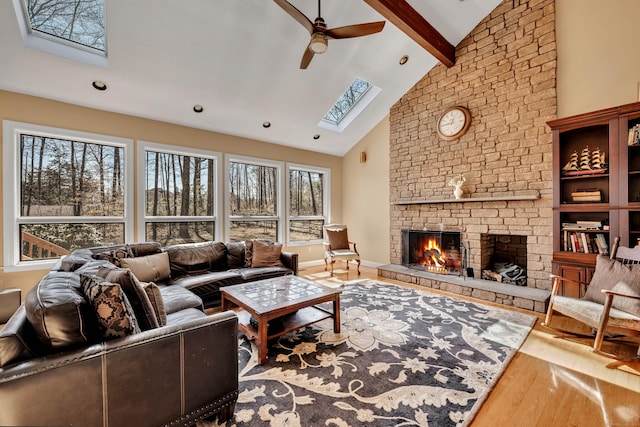 living room featuring beam ceiling, high vaulted ceiling, wood finished floors, a large fireplace, and a skylight